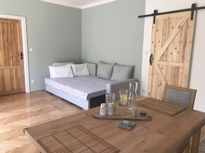 A room with a bed, a sofa, a wooden table with a tray, and a barn-style door. - Lovely And Freshly Renovated Apartment In Praha 10 (Prague)