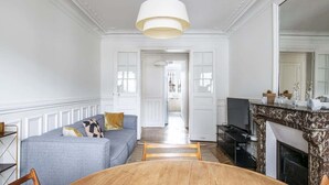 A spacious living room with a grey sofa, wooden dining table, and a fireplace.