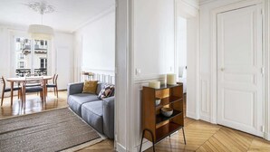 A modern living room with a grey sofa, wooden coffee table, and a glass shelving unit.