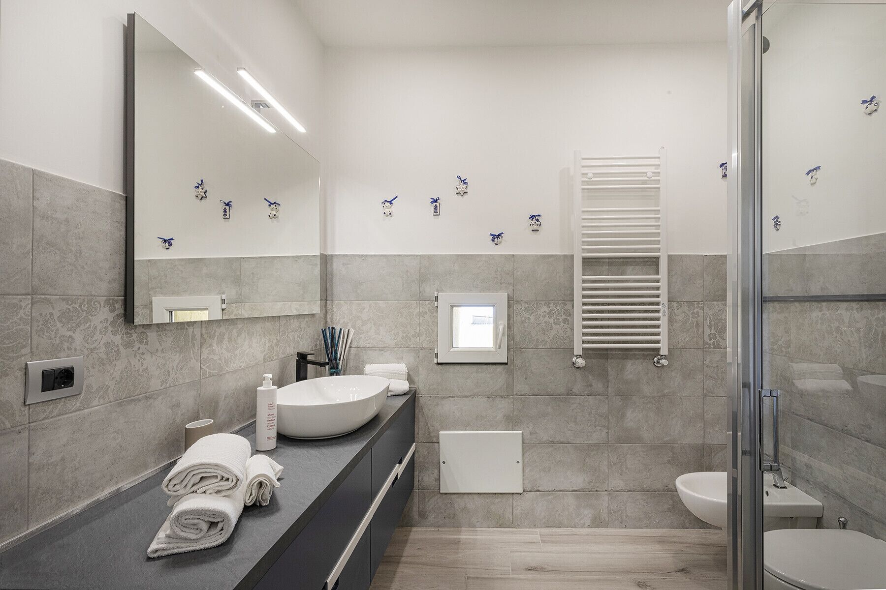 Une salle de bain moderne avec un grand miroir, un lavabo rond, des toilettes et un espace douche.
