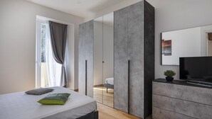 Un dormitorio moderno con una cama, un televisor y un amplio armario.