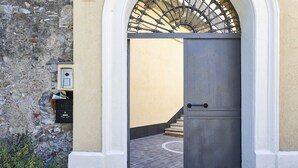 Puerta cerrada con reja metálica, buzón y pared de piedra.