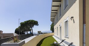 Un bâtiment moderne doté d’un chemin sinueux, d’un espace extérieur aménagé pour s’asseoir et d’une vue sur la mer.