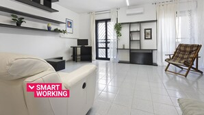 A modern living room with a sofa, a chair, a TV, and a bookshelf. - Casa Giovanna by Wonderful Italy (Bari)