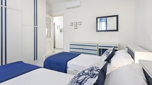 A hotel room with two beds, a wardrobe, a mirror, and a small window. - Casa Giovanna by Wonderful Italy (Bari)