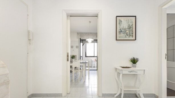 A hallway with a white door, a white console table with a plant, and a framed picture on the wall. - Casa Giovanna by Wonderful Italy (Bari)