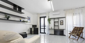 Una sala de estar moderna con un sofá, una silla, un televisor y una estantería.