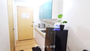 A compact kitchen with a toaster, a small refrigerator, and a potted plant. - Room-butler's Bnb B Trees Residences Qc (Quezon City)