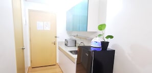 A compact kitchen with a toaster, a small refrigerator, and a potted plant. - Room-butler's Bnb B Trees Residences Qc (Quezon City)