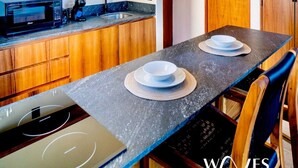 A modern kitchen with wooden cabinets, a built-in microwave, and a dining table with plates and a bowl. - Studio Ph Private Rooftop Pool Great Located (Tulum)