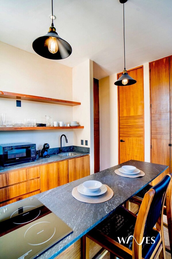 Una cocina moderna con armarios de madera, microondas integrado y una mesa de comedor con platos y un tazón.
