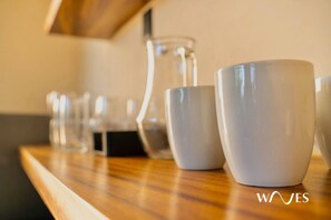 Una mesa de madera con varias tazas blancas de cerámica y un jarro de vidrio transparente.