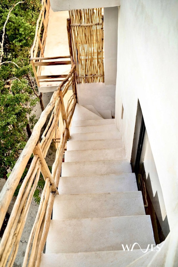 Una escalera con barandilla de bambú que conduce a una pared blanca.