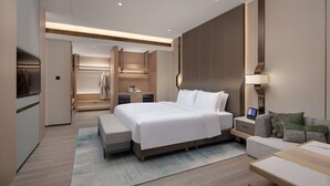 A modern hotel room with a large bed, bedside tables, a sofa, and a desk with a lamp. - Wyndham Garden Chuxiong Downtown (Chuxiong Yi)