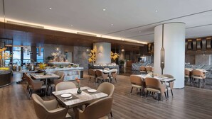 A spacious restaurant with multiple seating areas, a central bar, and a marble countertop. - Wyndham Garden Chuxiong Downtown (Chuxiong Yi)