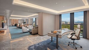 A modern hotel lobby with a curved reception desk, seating area, and large windows offering a city view. - Wyndham Garden Chuxiong Downtown (Chuxiong Yi)