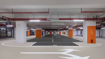 A multi-level parking garage with clearly marked parking spaces, directional arrows, and emergency equipment.