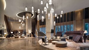 A spacious lobby with a modern design, featuring a central staircase, multiple seating areas, and a variety of lighting fixtures. - Wyndham Sun Moon Lake (Yuchi)