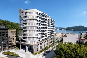 Un hotel de varias plantas con diseño moderno, con balcones y vista al agua.