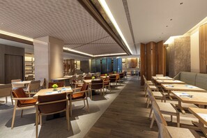 Un moderno vestíbulo de hotel con una larga recepción, varias zonas de estar y un pasillo central.
