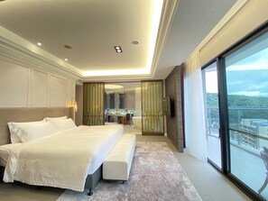 Una habitación de hotel moderna con una cama grande, un baño con tocador y un balcón con vista a la ciudad.