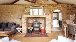 A cozy living room with a stone fireplace, wooden beams, and a sofa.