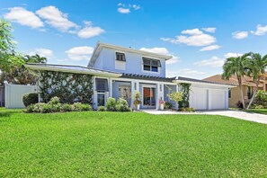 A modern two-story house with a well-maintained lawn, a covered porch, and a garage.