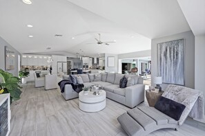 A modern living room with a sectional sofa, a coffee table, and a dining area in the background.
