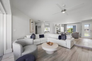 A modern living room with a sectional sofa, a round coffee table, and a ceiling fan.