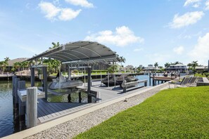 Un port de plaisance avec des bateaux amarrés, un espace abrité et un salon au bord de la piscine équipé de chaises.