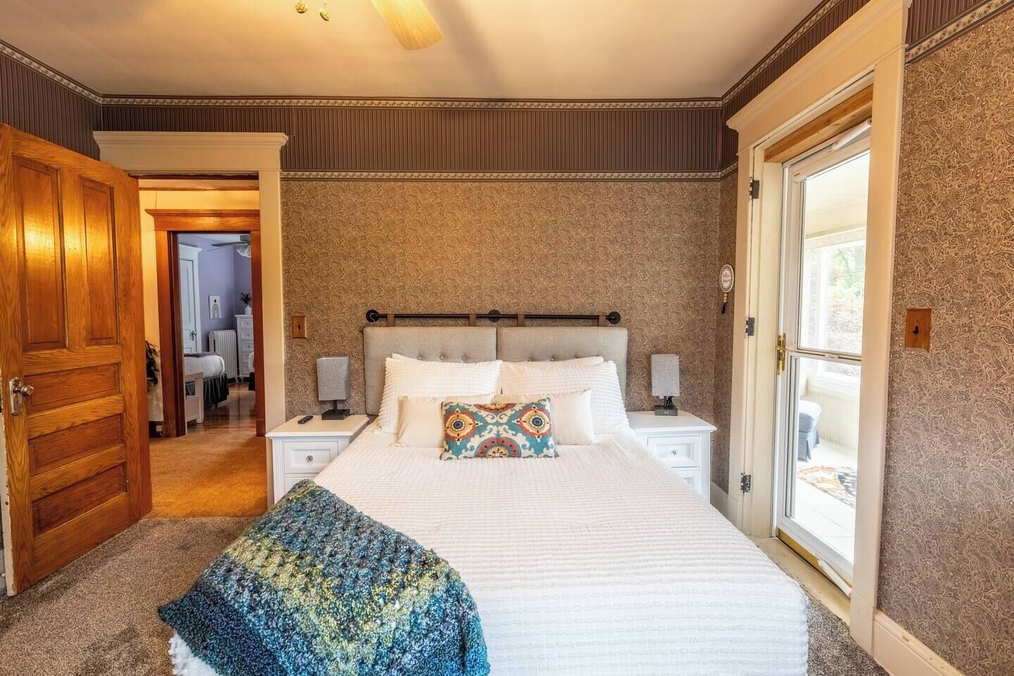 Un dormitorio con una cama grande, dos mesitas de noche, un cabecero y una ventana.