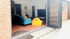An open living area with a sofa, a yellow bean bag, and a TV.