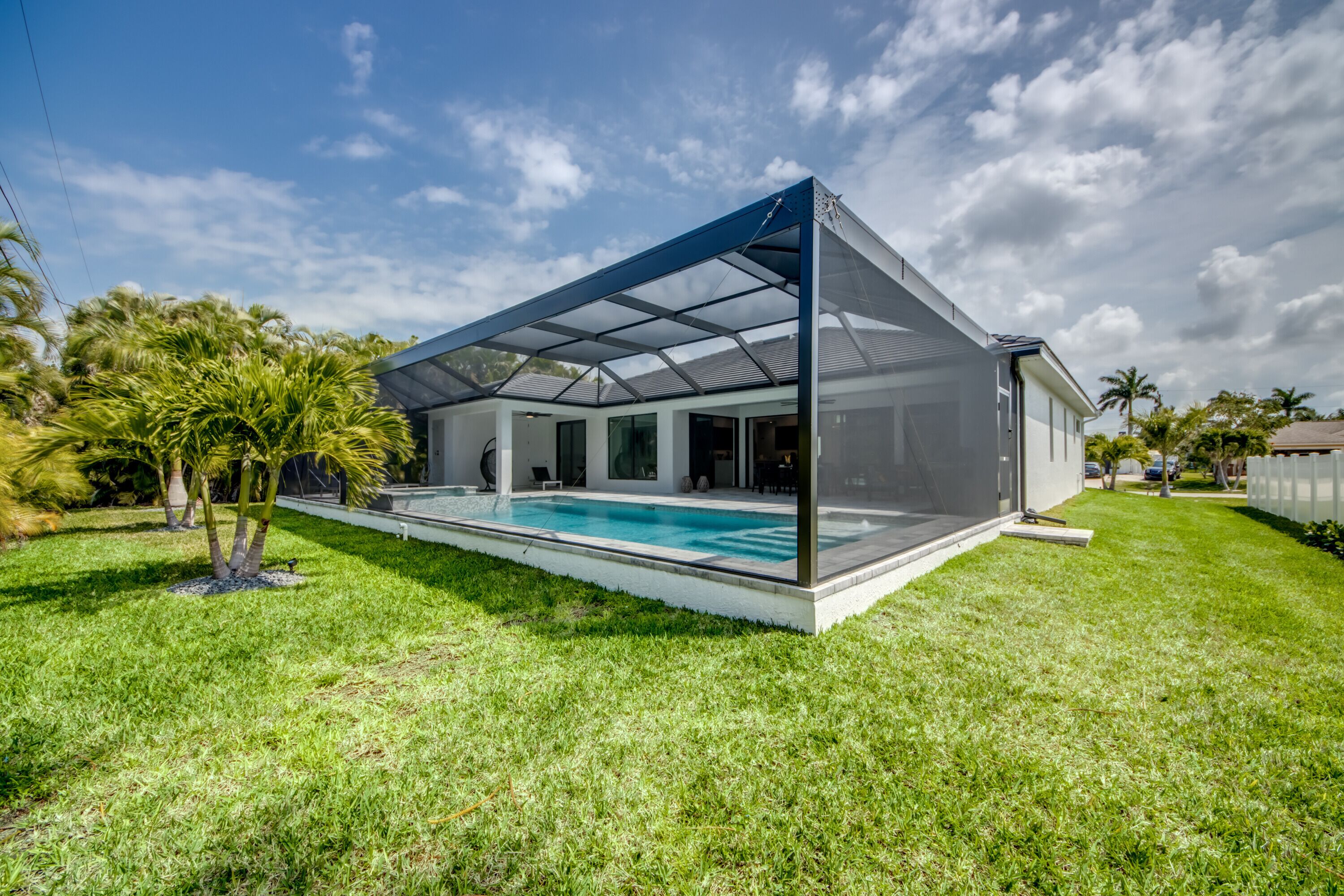 A modern house with a glass-enclosed patio and a swimming pool.
