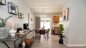 Une cuisine moderne avec un coin repas, comprenant une table en bois, des chaises et une machine à café.