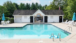 Une piscine avec un bâtiment blanc en arrière-plan, une zone délimitée par une clôture et un drapeau au sommet.