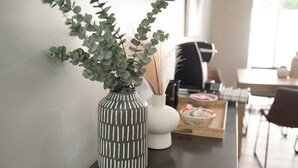 Une cuisine moderne avec un plan de travail foncé, un vase rayé contenant des feuilles vertes, un vase blanc et un plateau en bois sur lequel sont disposés des aliments.