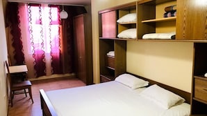 A bedroom with a bed, a desk, and a wardrobe with shelves. - Room-enki's Guesthouse Tirana (Tirana)