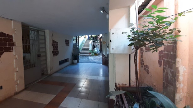 A narrow hallway with a tiled floor, a door with a metal gate, and a staircase leading to an upper level. - Room-enki's Guesthouse Tirana (Tirana)