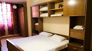 A bedroom with a large bed, wooden shelving, and a wardrobe. - Room-enki's Guesthouse Tirana (Tirana)
