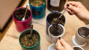 Una persona preparando té con varios recipientes y utensilios sobre una superficie de madera.