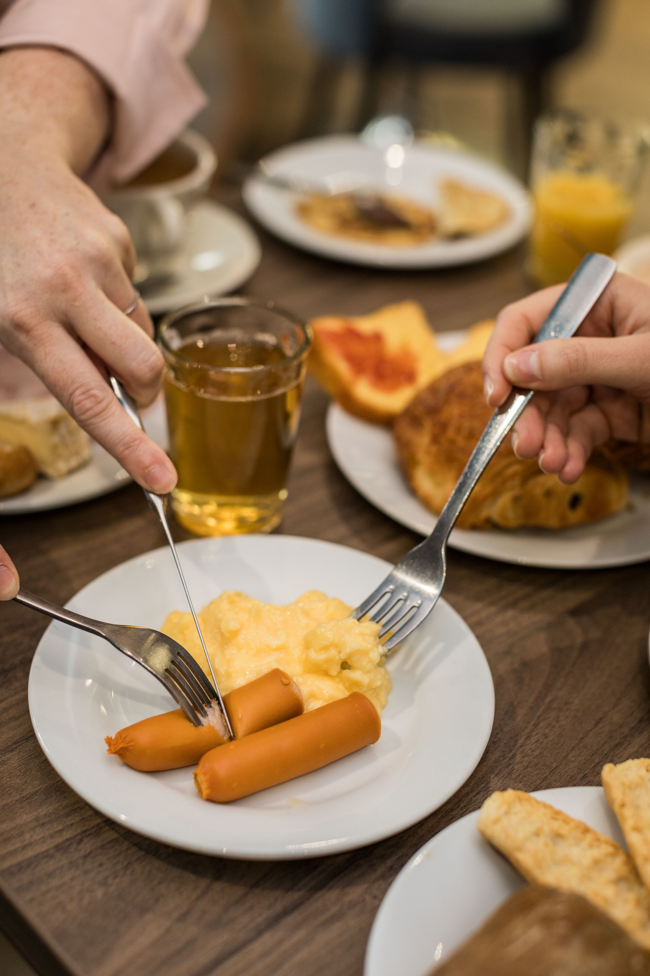 Een eettafel met borden eten, onder meer worst en roerei.