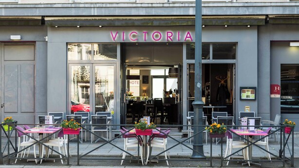 A hotel named 'VICTORIA' with outdoor seating and flower planters. - Hôtel Restaurant Le Victoria (Rennes)