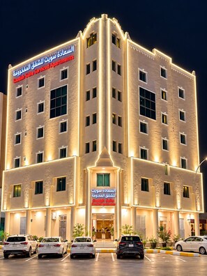 A multi-story hotel with a prominent entrance and a parking lot with several cars. - السعاده سويت للشقق المخدومه (Riyadh)