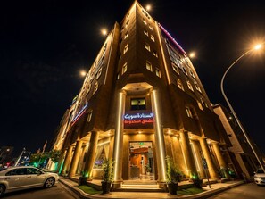 Een hotel met meerdere verdiepingen, een opvallende entree, grote zuilen en verlichte signage.