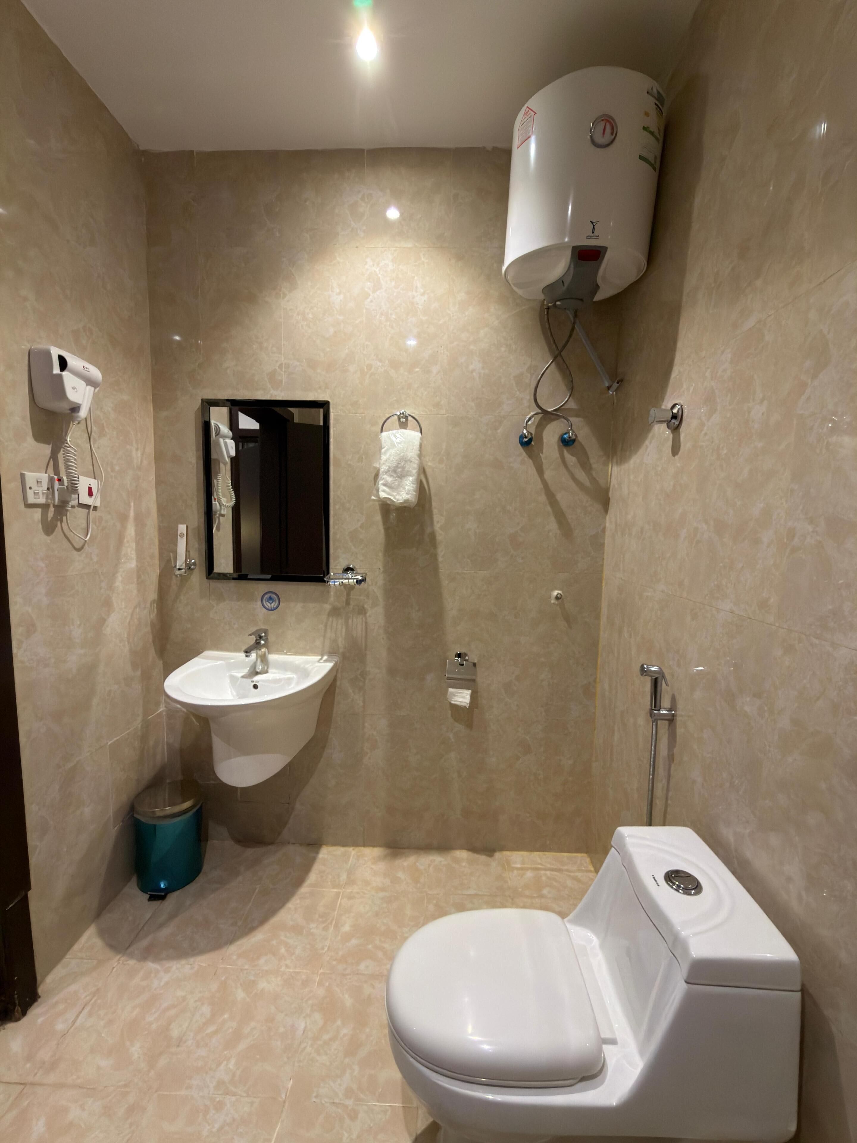 A bathroom with a toilet, sink, and a hand dryer mounted on the wall.
