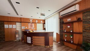 A reception area with a wooden reception desk, a clock, and a wall-mounted air conditioner. - السعاده سويت للشقق المخدومه (Riyadh)