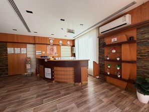 A reception area with a wooden reception desk, a clock, and a wall-mounted air conditioner.