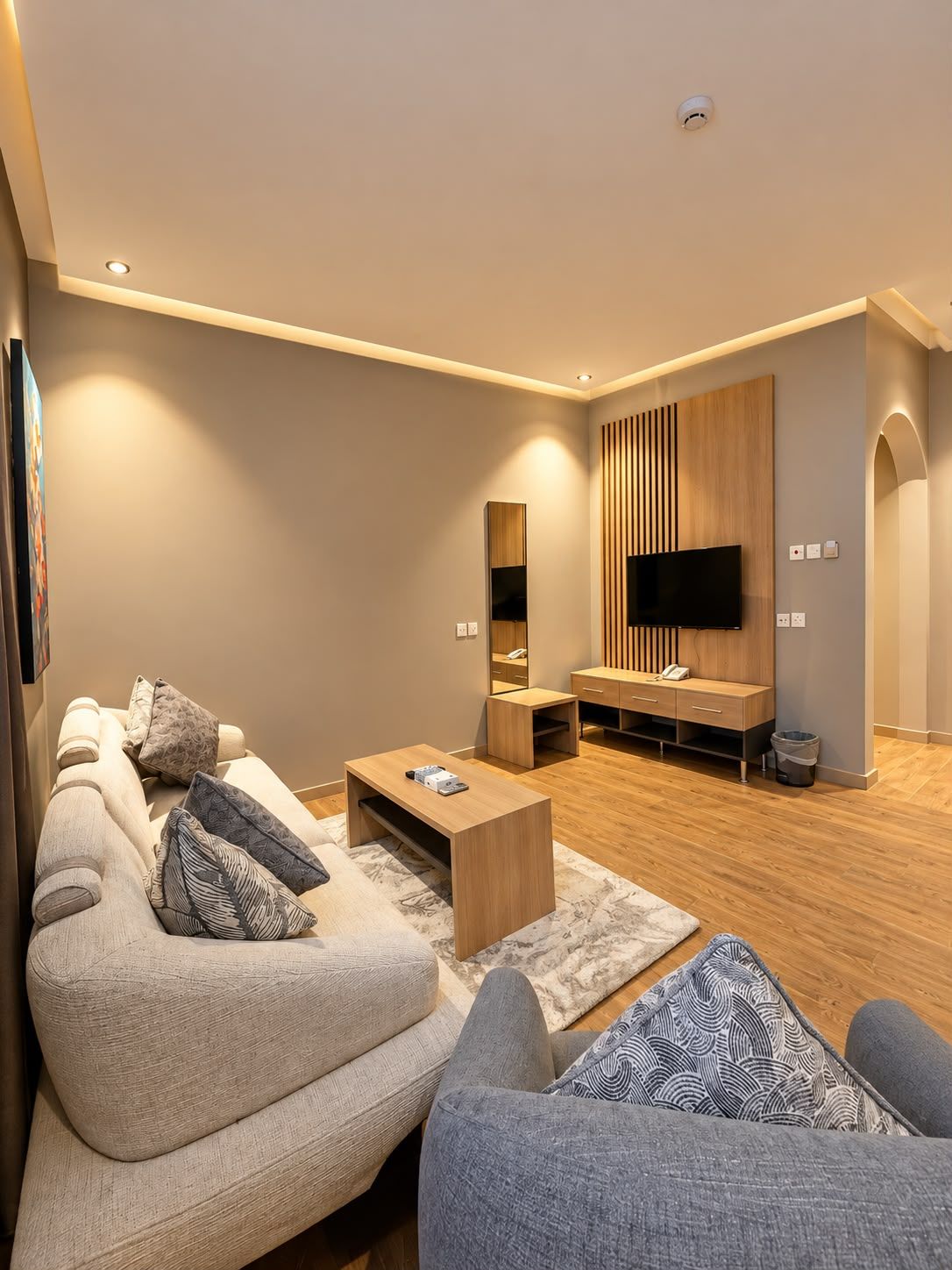 Una sala moderna con un sofá modular, una mesa de centro, un televisor y un mueble de madera para entretenimiento.