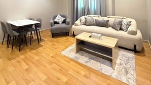 A modern living room with a sofa, armchair, dining table, and coffee table. - السعاده سويت للشقق المخدومه (Riyadh)