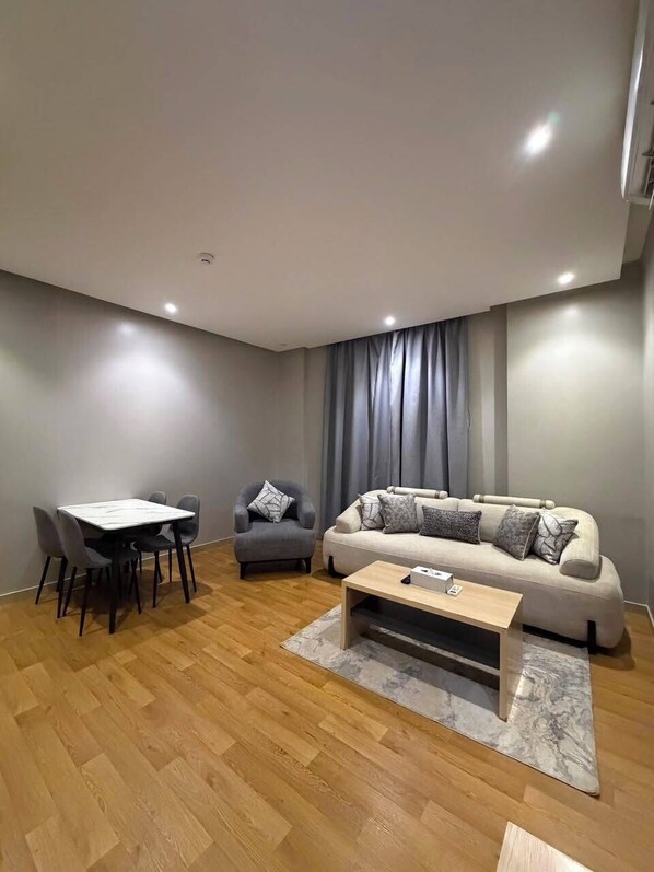 Een moderne woonkamer met een bank, een salontafel en een eethoek met stoelen.
